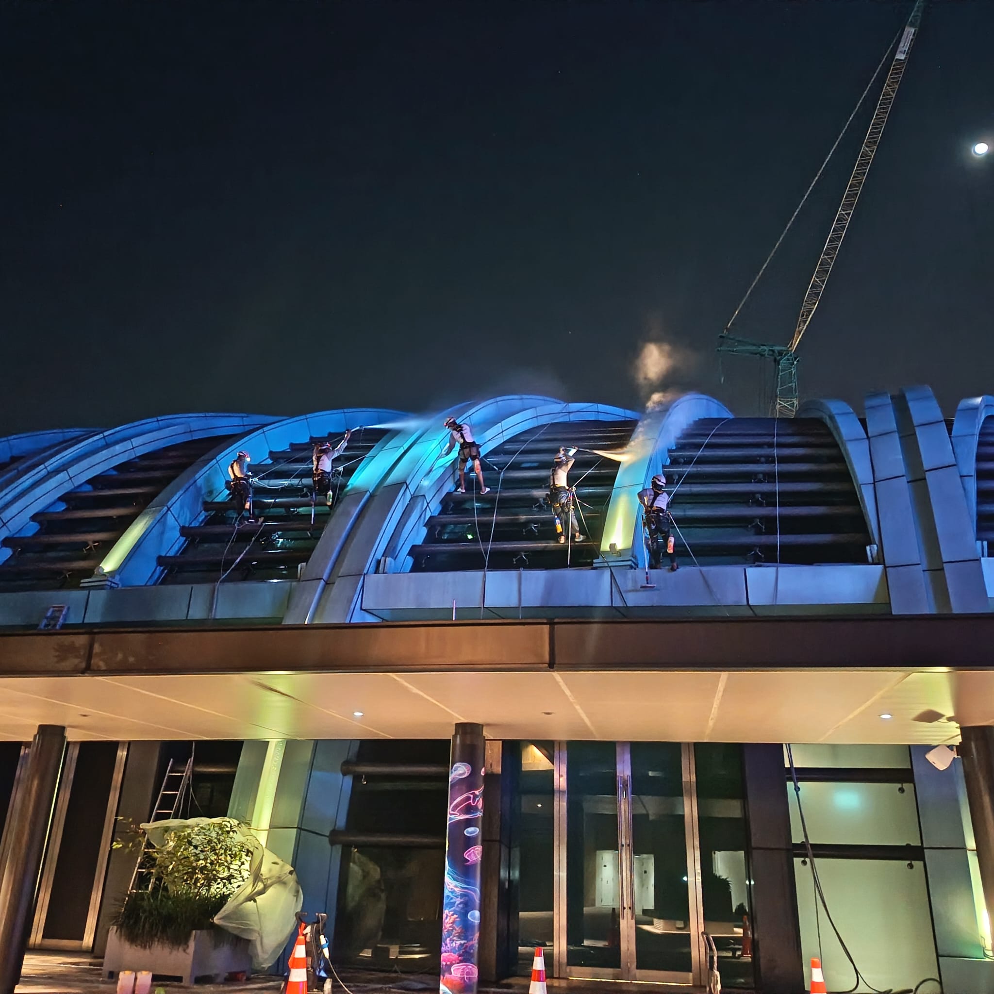 Workers cleaning a curved facade at night